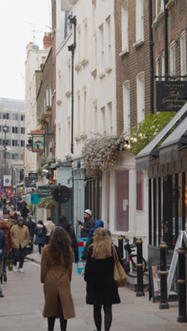 Vertikales-Video-Von-Geschäften-Und-Restaurants-Mit-Menschen-In-Einer-Reihe-In-Mayfair,-London,-Großbritannien